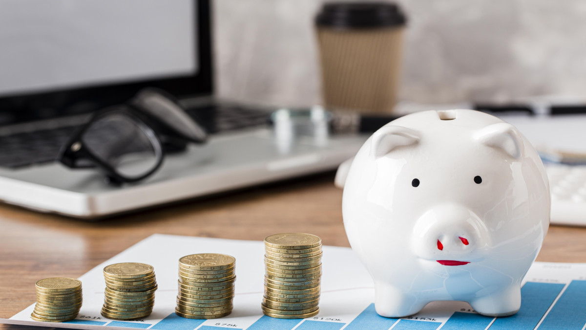 tirelire accompagné de quelques pièces de monnaie devant un ordinateur